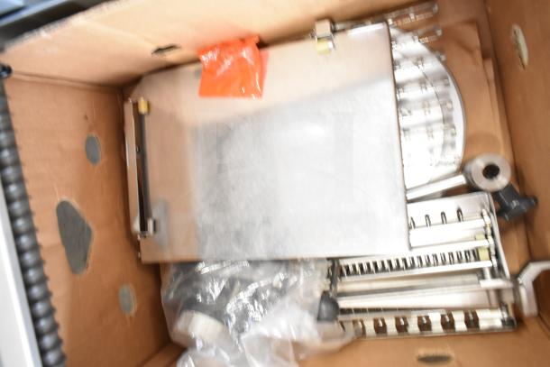 Bizerba A 404 US commercial countertop meat slicer stacker in a cardboard box, showing metal components; 115 volts, 1 phase.