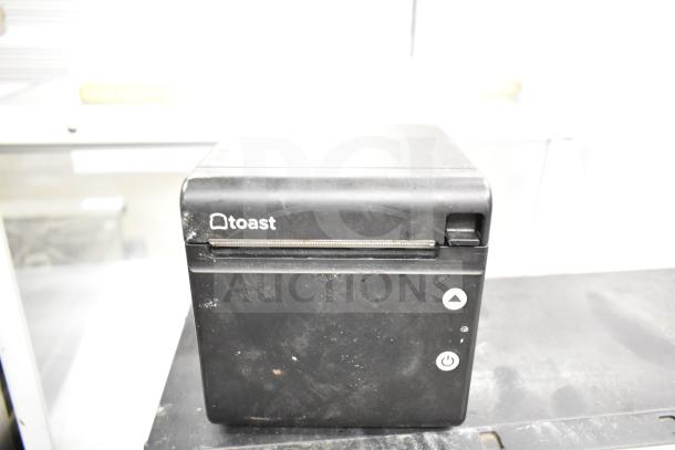 Toast TP200 receipt printer, black, visible wear on surface, with brand logo and control buttons shown on front.