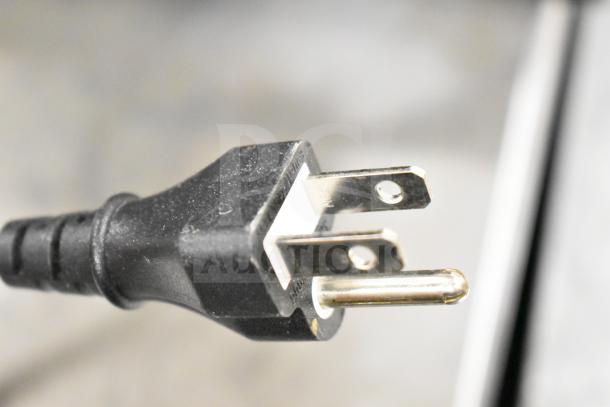 Close-up of a black, three-pronged power cord plug. No other auction items visible.