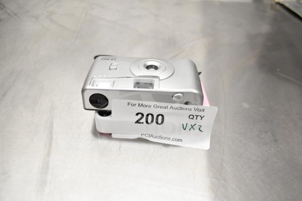 Two cameras for auction: VF201 Film Camera and Kodak Printomatic 8mm, shown stacked. Includes auction tag "200 VX2."