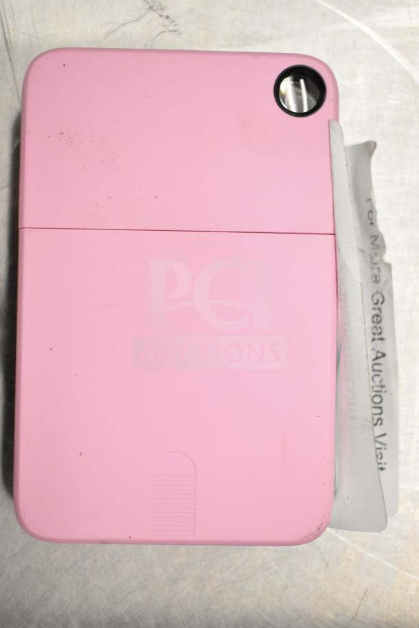 Pink Kodak Printomatic 8mm camera, showing lens and slightly worn condition. Auction label partially visible.