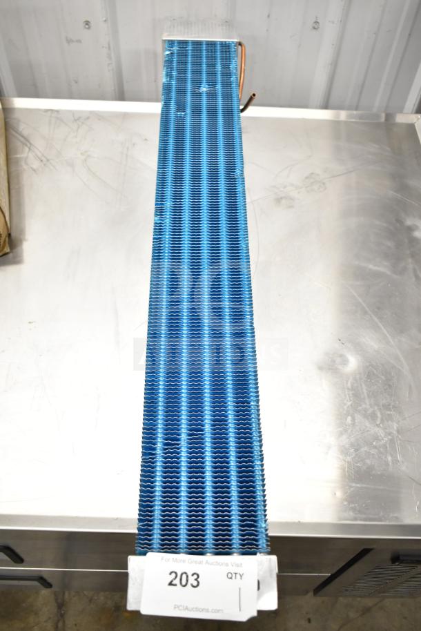 Blue evaporator coil with fins, in excellent condition, on a metal surface. Auction tag number 203 is visible.