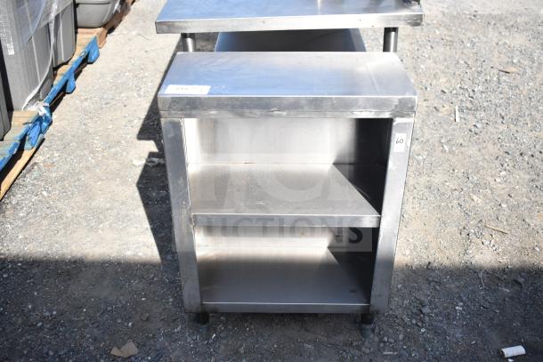 Commercial stainless steel counter with two under shelves, lightly scuffed, suitable for kitchen or storage use.