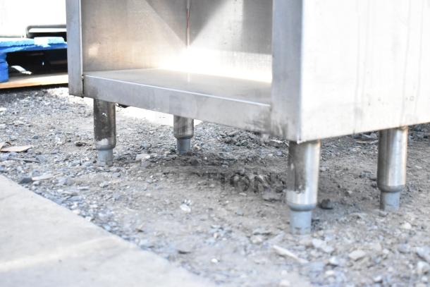 Commercial stainless steel counter with two under shelves. Visible sturdy legs and durable design, suitable for heavy-duty use.