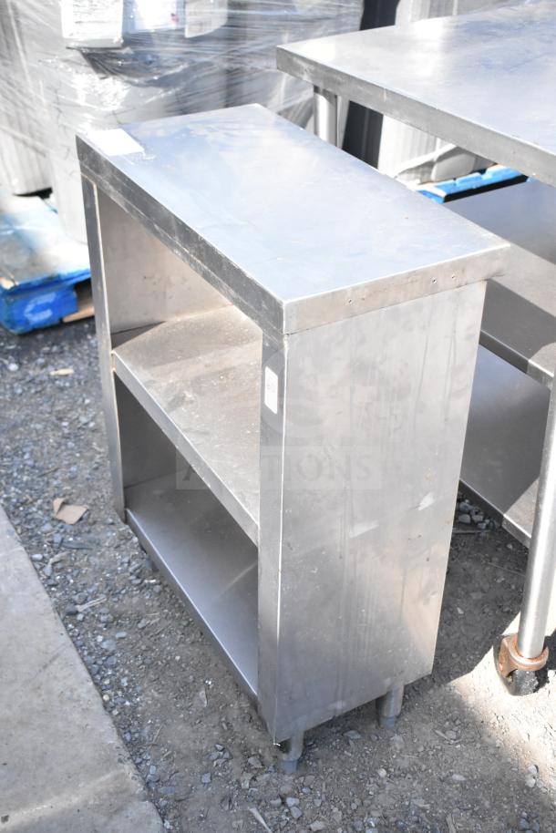 Commercial stainless steel counter with two under shelves, durable design, minor surface wear, ideal for kitchen use.