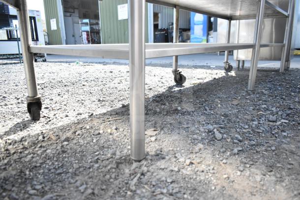 Commercial table with two under shelves, stainless steel, on wheels, suitable for kitchen or workshop use. Excellent condition.