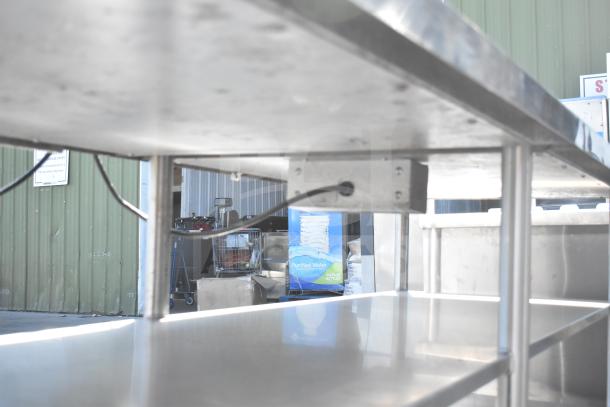 Stainless steel commercial table with two under shelves, sturdy frame, in good condition, ideal for kitchen or workspace use.
