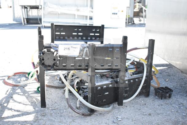4 soda pumps on a black metal soda box rack, showing plastic hoses and fittings, labeled "216" for auction identification.