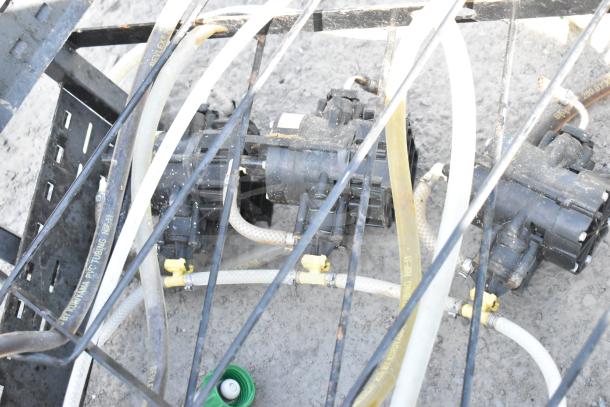 Four soda pumps connected to a black metal soda box rack, with attached tubes and visible wear.