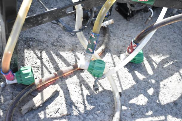 4 soda pumps attached to a black metal rack, featuring branded hoses, used condition, for dispensing beverages.