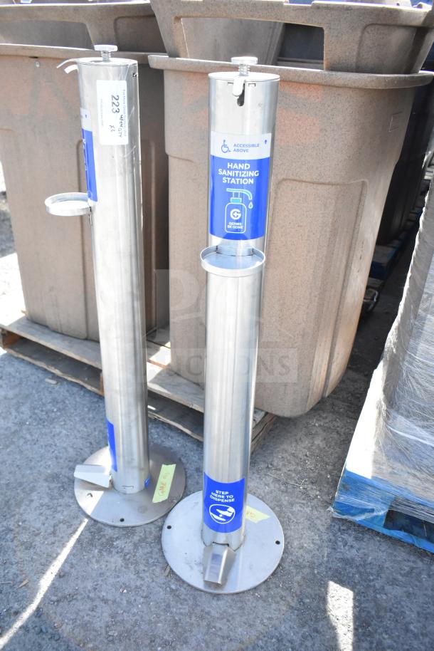 Two stainless steel hand sanitizing stations with foot pedal operation, blue signage, and accessible design.