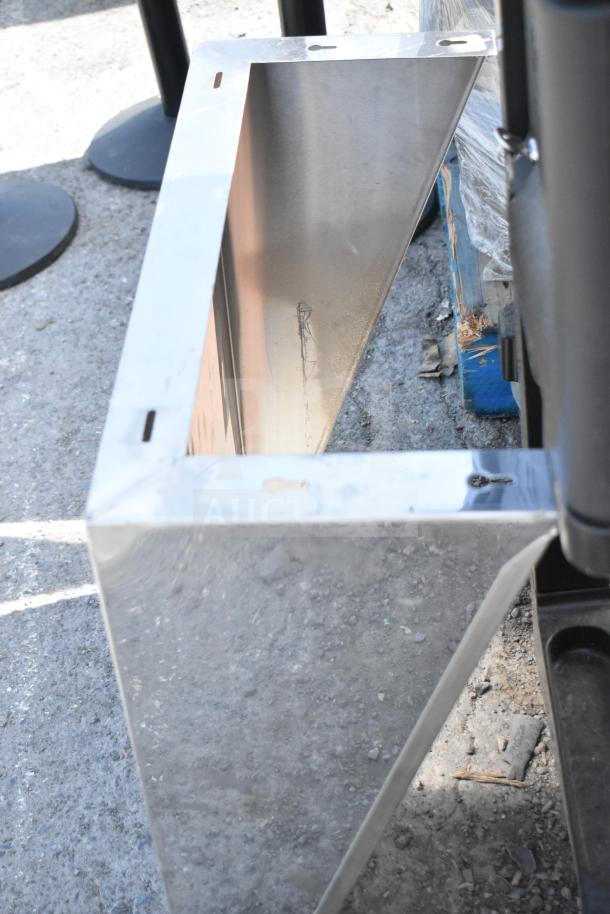 Stainless steel wall mount shelf with mounting holes, slightly scratched surface, suitable for kitchen or storage use.