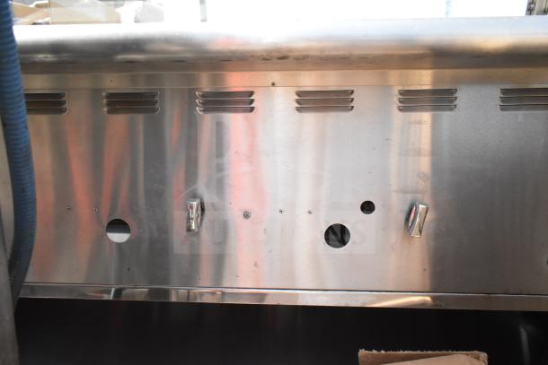 Commercial hot food merchandising case with stainless steel front panel, ventilation slots, and metal control knobs.