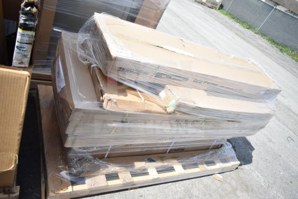 Stack of boxed items wrapped in plastic on a pallet, labeled "Scratch and Dent." Visible tags indicate table, strip warmer, and pan rack. Brand tags include Regency.