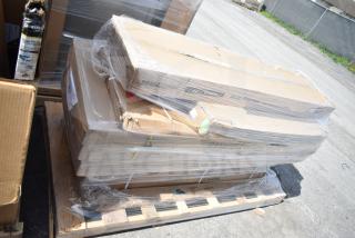 Stack of boxed items wrapped in plastic on a pallet, labeled "Scratch and Dent." Visible tags indicate table, strip warmer, and pan rack. Brand tags include Regency.