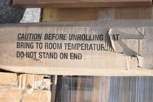 Cardboard box with caution label reading "Caution Before Unrolling Mat" and visible damage, part of auction lot.