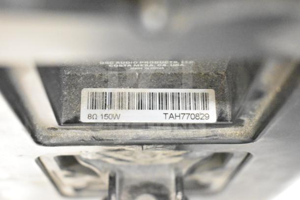 Close-up of a QSC AD-S6T speaker label showing "8Ω 150W" and serial "TAH770829", housed in Costa Mesa, CA, USA.