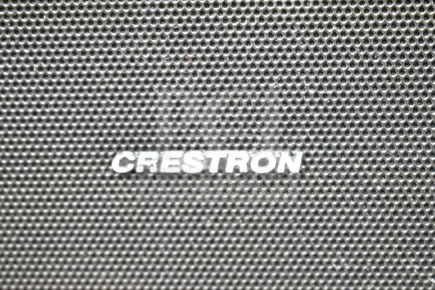 Alt text: Close-up of Crestron speaker grill with brand logo. Part of an auction of 8 speakers, including 1 QSC AD-S6T.