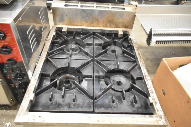 Commercial countertop natural gas 4 burner range, metal finish, used condition with visible wear and control knobs.