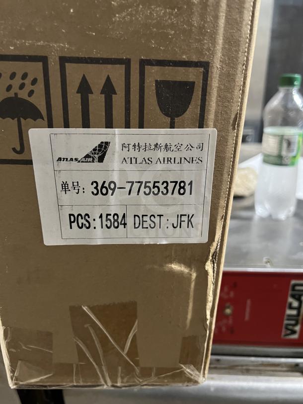 Cardboard box marked with shipping symbols and "ATLAS AIRLINES" label, addressing 1584 pieces to JFK.