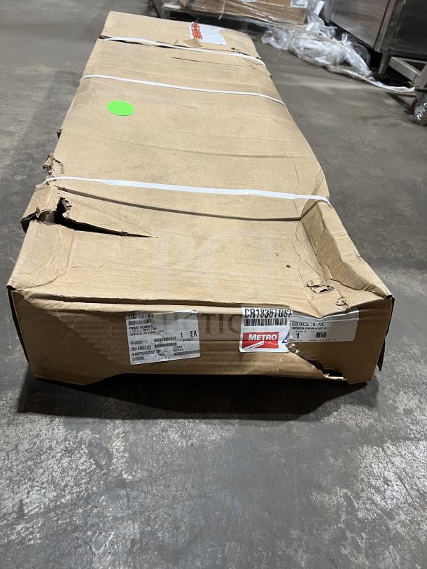 Damaged box labeled "Metro" containing a Cambro ESU247284V5580 stainless steel 5-tier shelving unit on legs.