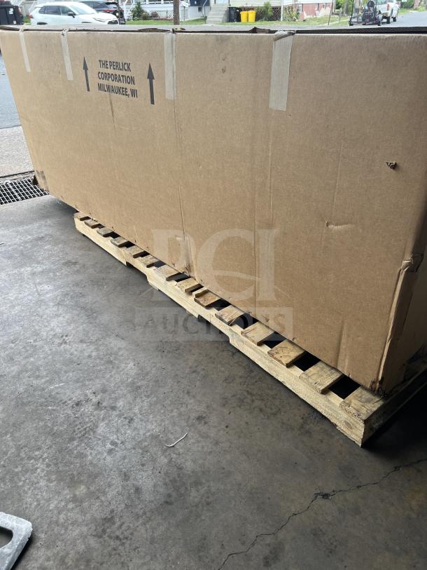 Cardboard box containing a new Perlick BBS108RFYSSH1 4-door bar back refrigerator, with stainless steel worktop, on a wooden pallet.