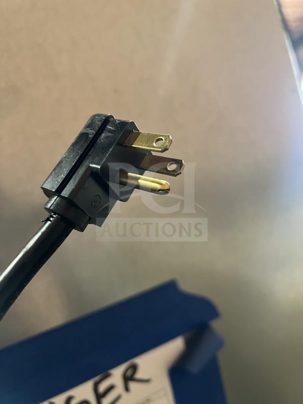 Close-up of a power plug for Hoshizaki F1A-FS freezer. Background shows partial label with marker writing.