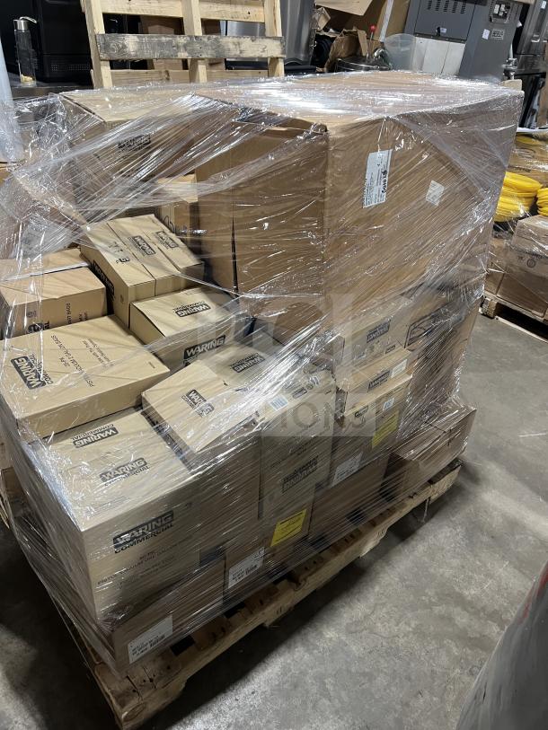 Shrink-wrapped pallet of mixed Waring and Adcraft commercial kitchen supplies, including vacuum bags, blender jars, condiment dispensers, and wire shelves. Boxes are labeled with models and quantities.