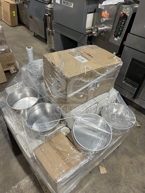 Mixed pallet of commercial kitchen items: onion soup crocks, mugs, fruit dishes, platter plates, and cake pans, new in boxes.