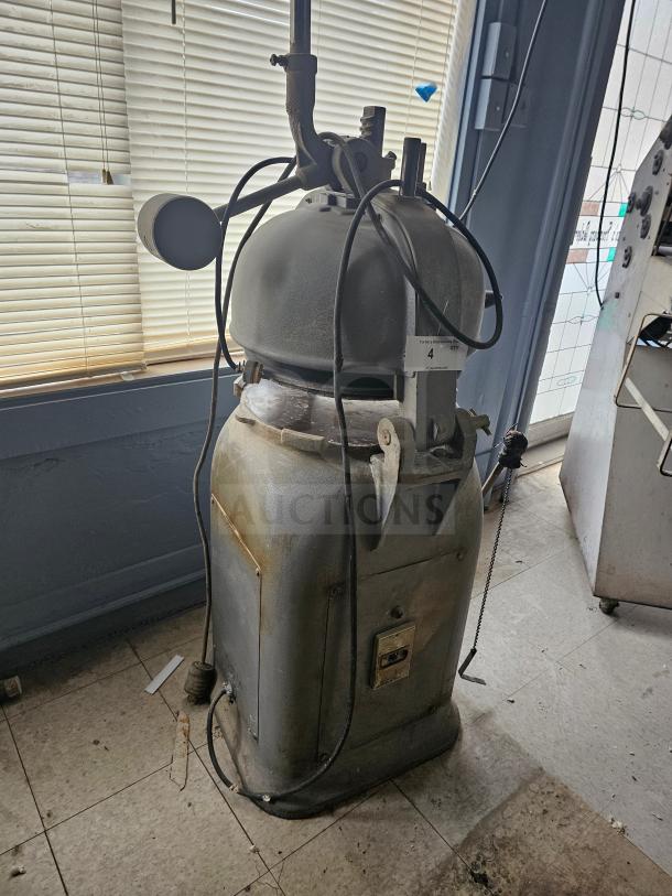 Commercial dough divider in used condition, featuring a sturdy metal body and lever mechanism. Visible wear and label markings.