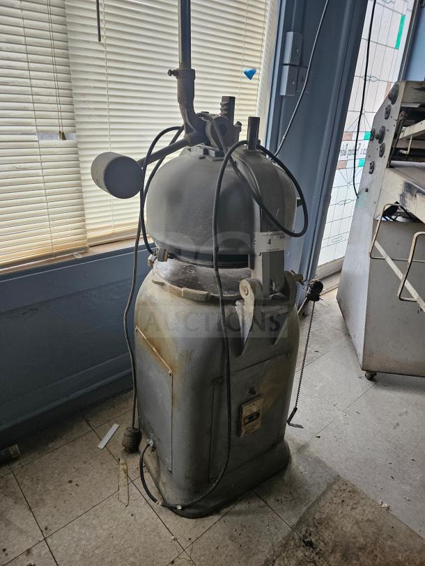 Commercial dough divider in used condition, featuring a large round top and multiple levers. Visible wear and power cord attached.