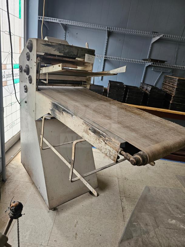 Commercial dough sheeter with rust and wear, featuring adjustable rollers and conveyor belt. Needs maintenance. Ideal for bakeries.