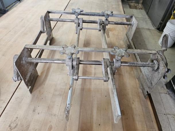 Vintage commercial dough sheeter with metal frame showing signs of wear, featuring adjustable knobs and roller mechanism.