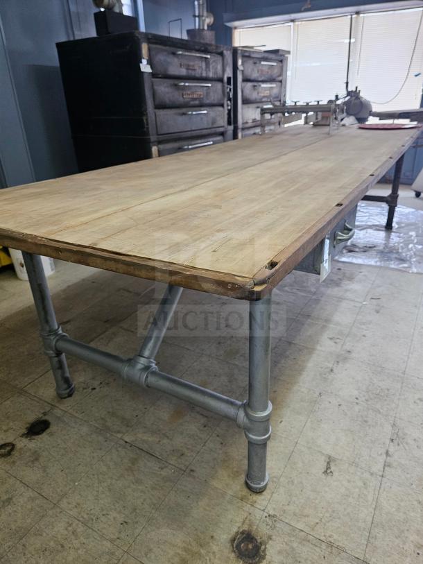 12Ft wood top work table with metal pipe legs, in good condition. Sturdy construction, suitable for industrial use.