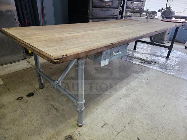 12Ft wood top work table with metal pipe legs and a metal drawer. Good condition, ideal for workshop use.