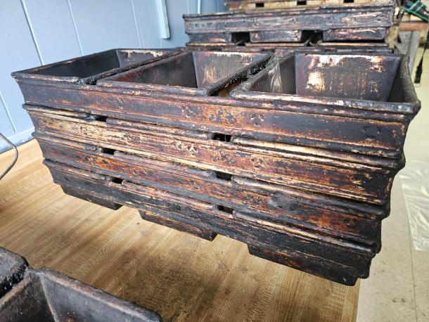 Vintage industrial baking pan with six compartments, heavily worn with rust and patina, showcasing a rustic appeal.