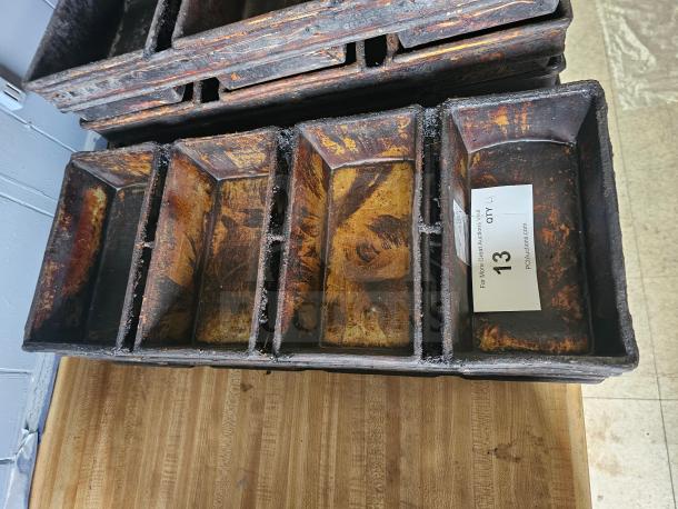 Alt text: Vintage multi-loaf metal baking pan with rust patina, five compartments, auction tag "13," on wooden surface.