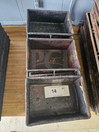 Stacked rectangular metal baking pans with rust and wear, numbered label "14" indicating auction lot.