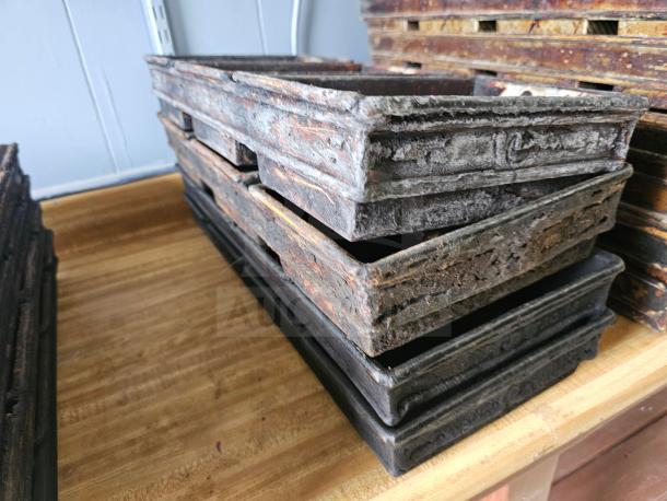 Stack of vintage rectangular baking pans with a weathered patina, showing signs of heavy use.