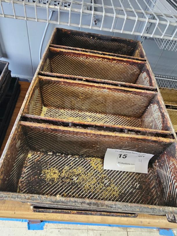 Rustic metal baking pan with ribbed interior, showing signs of wear and residue. Auction tag marked "15."