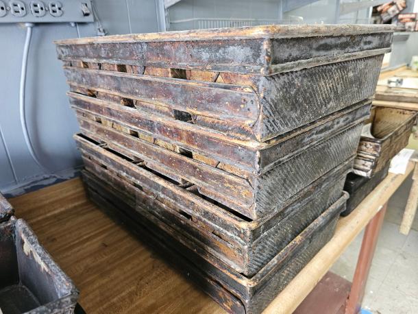 Stack of vintage metal baking pans with visible rust and patina, indicating age and use; ideal for collectors.