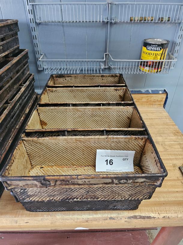 Metal baking pan with a ribbed interior, showing signs of rust and wear. Auction tag marked "16."