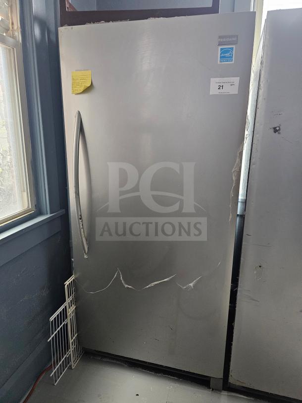 FRIGIDAIRE single door freezer, silver, Energy Star label, visible dents and scratches, auction tag marked "21".