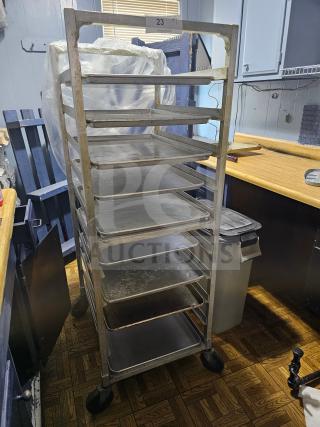 Sheet pan rack with multiple shelves, metal frame, on wheels. Used condition. Label reads "23." No contents included.