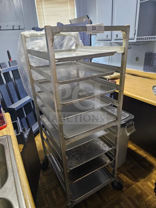 Stainless steel sheet pan rack on wheels, accommodates multiple pans, used condition, tagged "23."