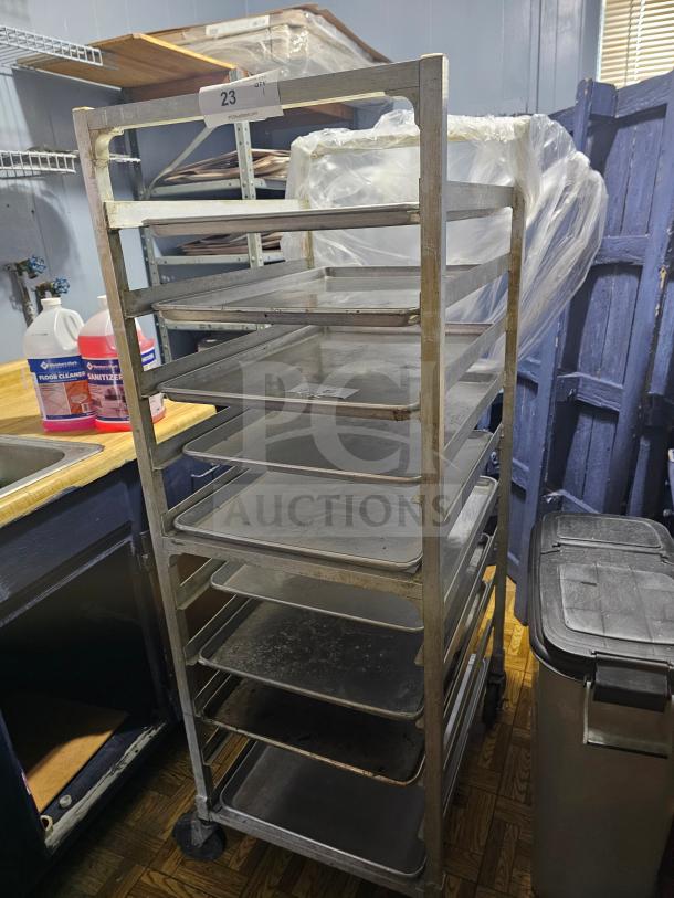 Metal sheet pan rack with multiple shelves, shows signs of use. Auction tag "23" attached. Content not included.