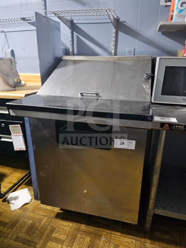 TRUE TWT-27 single door sandwich table in stainless steel, showing some wear. Includes top lid handle and visible unit number tag.