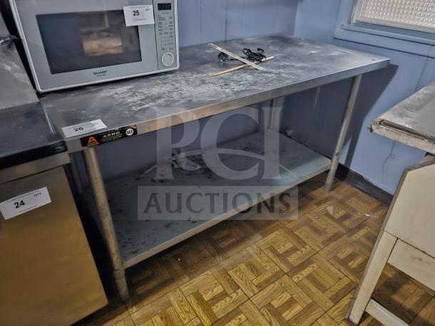 Stainless steel work table with undershelf, visible Aero and NSF labels, surface wear, ideal for kitchen use.