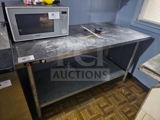 Stainless steel work table with undershelf, moderate wear, NSF certified, dimensions unknown, includes visible labels.