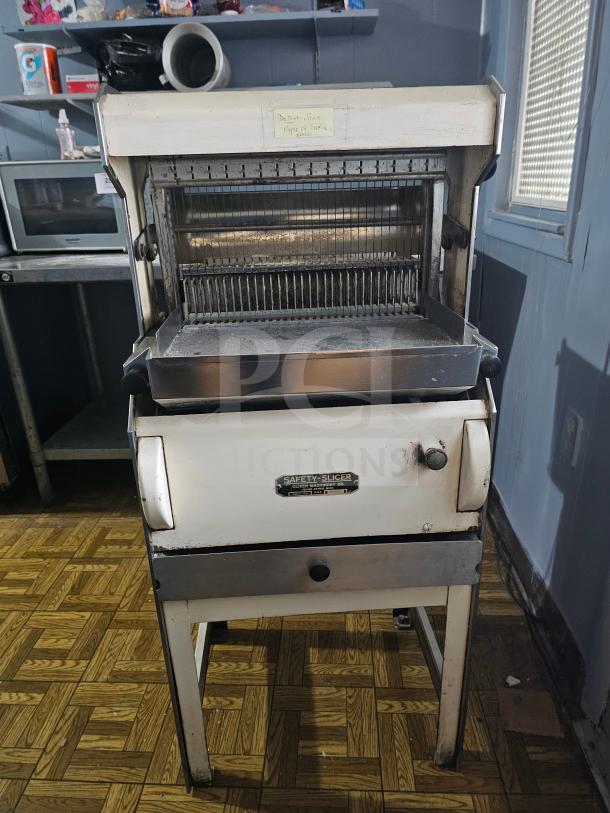 Oliver Machinery bread slicer, metal construction, shows wear. Safety-Slicer label visible. Ideal for bakery use.